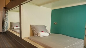 A single bed with a wooden headboard, a teal accent wall, and a mirror reflecting the room. - Lost & Found Dooms (Zanzibar Town)