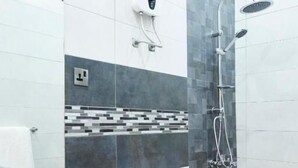 A modern bathroom with a white sink, toilet, and a shower with a handheld showerhead. - Lost & Found Dooms (Zanzibar Town)