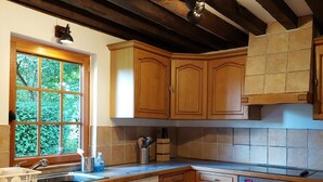Una cocina con armarios de madera, lavavajillas, horno y ventana con vistas a zonas verdes.