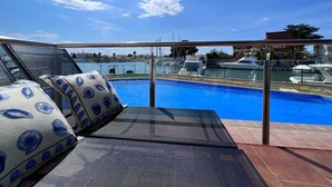 Ein Poolbereich mit Blick auf Boote und einen klaren Himmel.