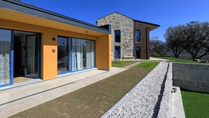 Una casa moderna con amplios ventanales, fachada de piedra y césped cuidado.