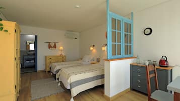 A bedroom with two beds, a desk, a chair, a wardrobe, and a small kitchen area.