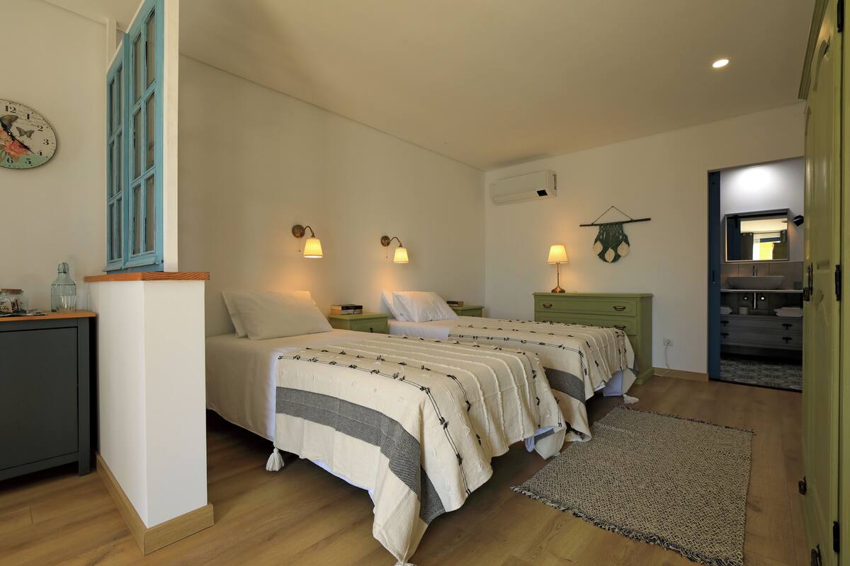 Ein Schlafzimmer mit zwei Betten, Nachttischlampen, einer Uhr und einem kleinen Schreibtisch mit Lampe.