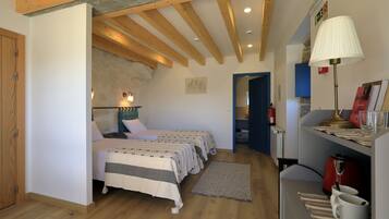 A bedroom with two beds, wooden beams, a lamp, a radiator, and a shelf with books and a kettle.