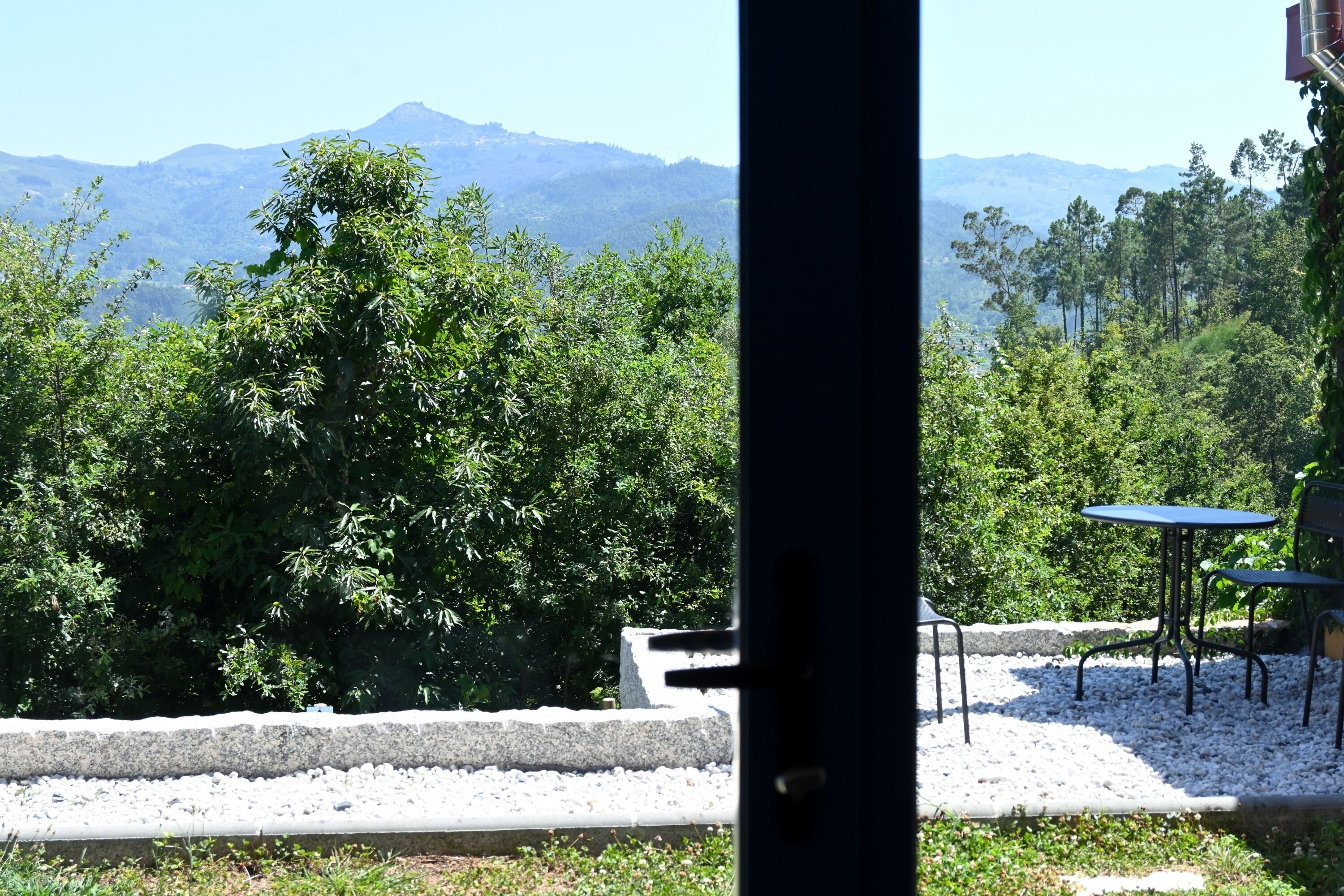 A patio area with a table and chairs, surrounded by trees and a view of distant mountains.