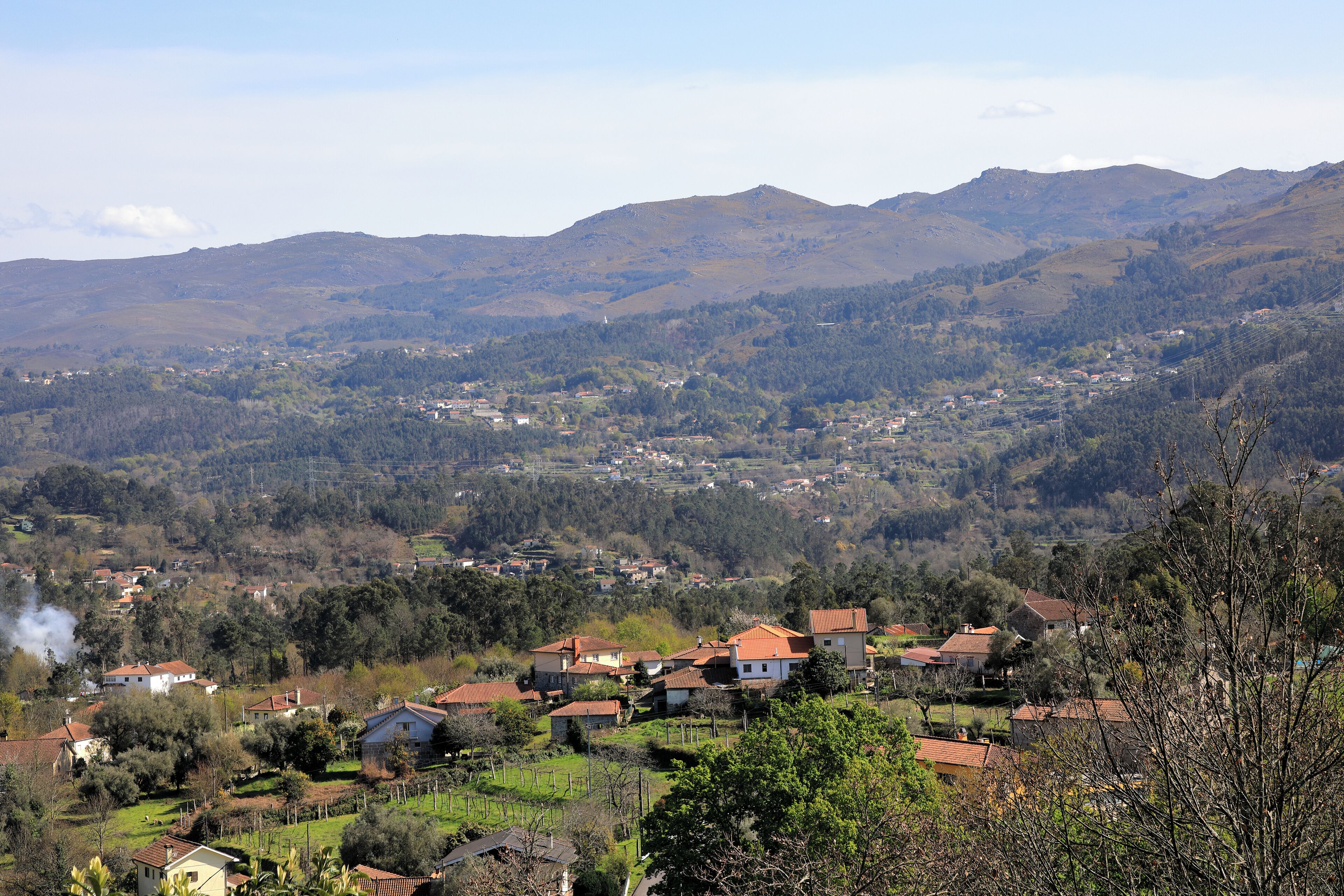 Un pueblo rural con casas, una iglesia y montañas al fondo.