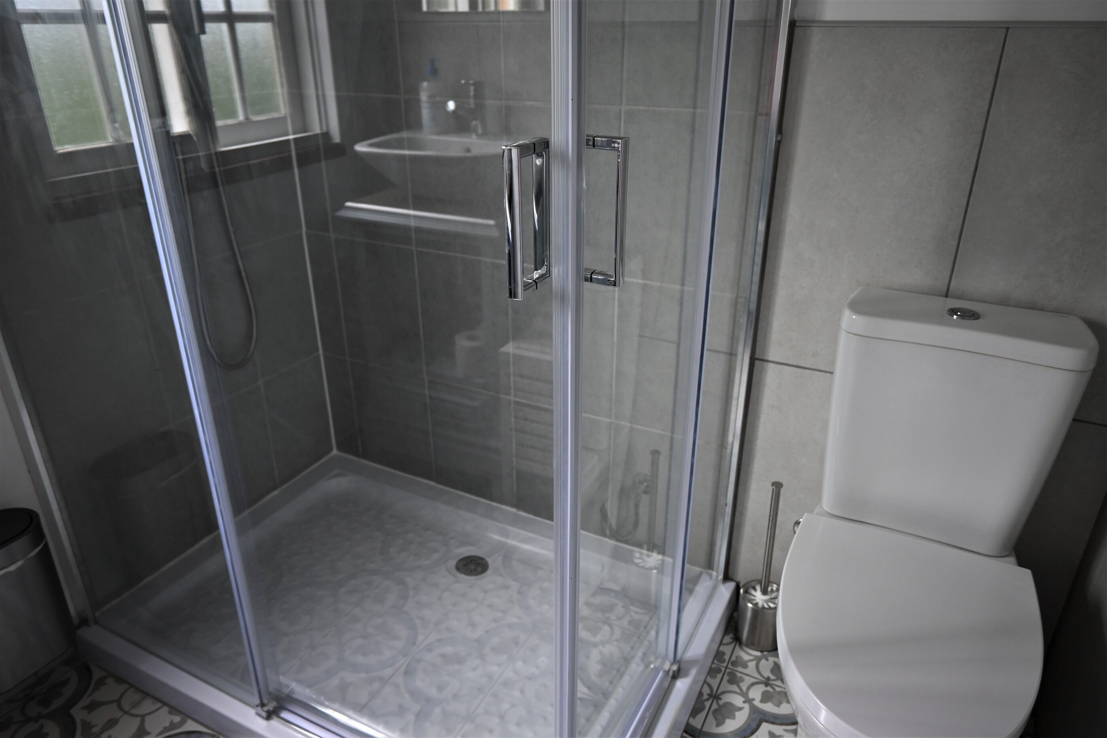 Un baño con ducha acristalada, inodoro y lavamanos.