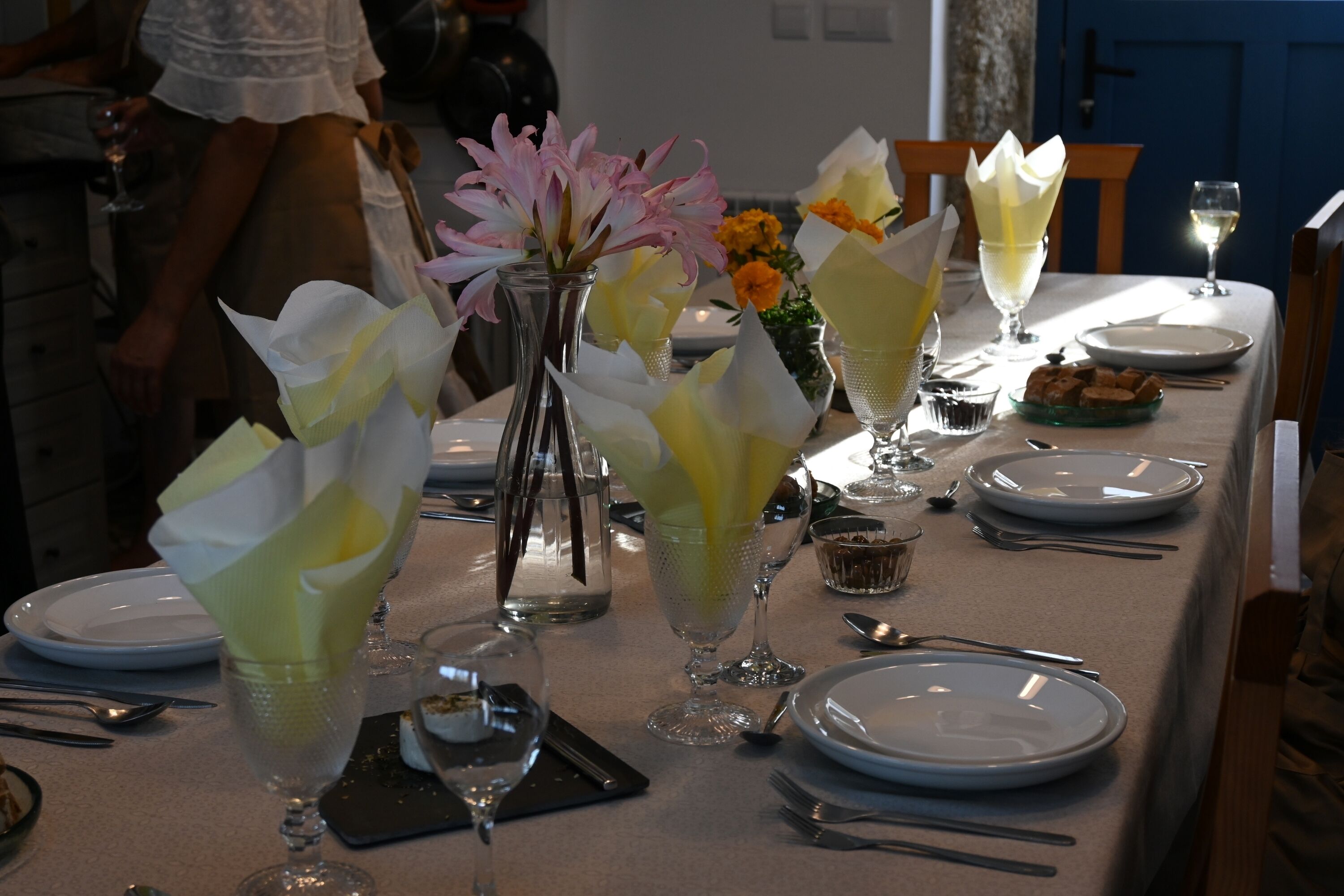 A dining table set with plates, glasses, and a vase with flowers.