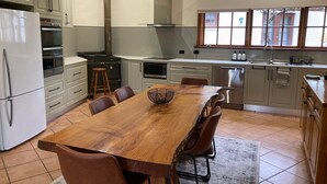 A modern kitchen with a wooden dining table, chairs, and a built-in oven. - Private Country Retreat Taradale Valley Tumbarumba in Snowy Mtns foothills.  (Tumbarumba)