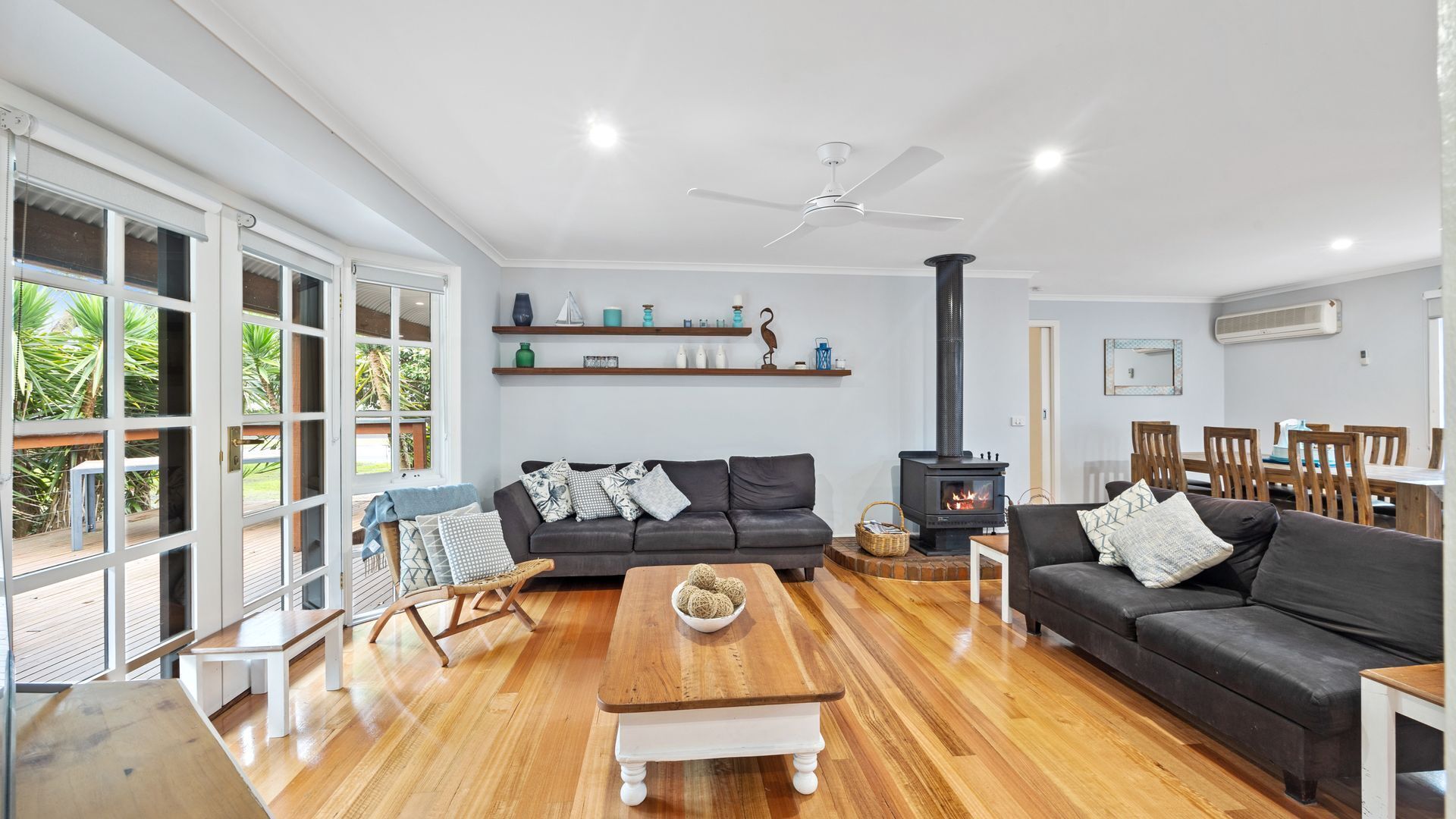 A spacious living room with a fireplace, sofas, a wooden coffee table, and a dining area.