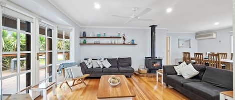 A spacious living room with a fireplace, sofas, a wooden coffee table, and a dining area.