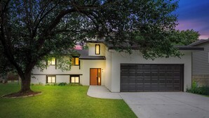 A modern two-story house with a well-maintained lawn, a garage, and a large tree in the front yard. - Beautiful 6 bed, 3 bath home in quiet neighborhood (Wichita)
