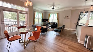 A spacious living area with a dining table, chairs, a sofa, and a TV.