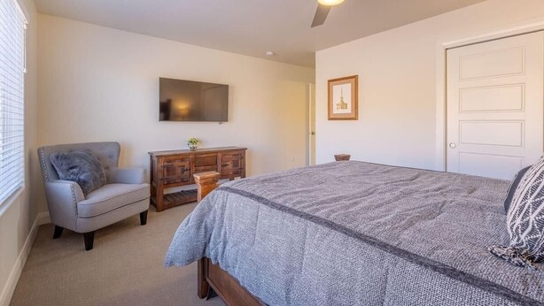 A bedroom with a bed, a chair, a dresser, a ceiling fan, and a door. - 5 BR - Siena Hills Resort - Patio, BBQ & Games (Washington)