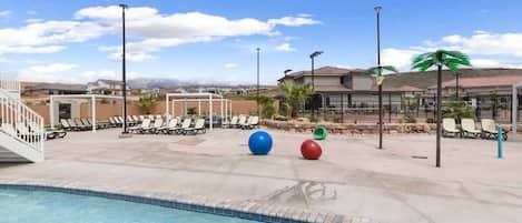 A swimming pool area with lounge chairs and exercise balls.