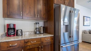 A kitchen with wooden cabinets, a stainless steel refrigerator, a coffee maker, and a toaster. - 5 BR - Siena Hills Resort - Patio, BBQ & Games (Washington)