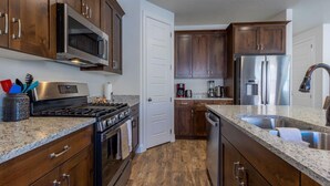 A modern kitchen with dark wood cabinets, stainless steel appliances, granite countertops, and a double sink. - 5 BR - Siena Hills Resort - Patio, BBQ & Games (Washington)