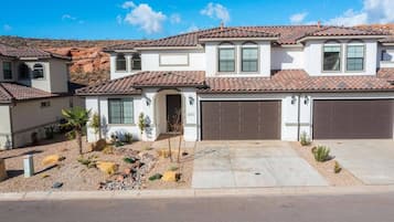 A two-story house with a tiled roof, a garage, and a landscaped front yard with small plants and rocks.
