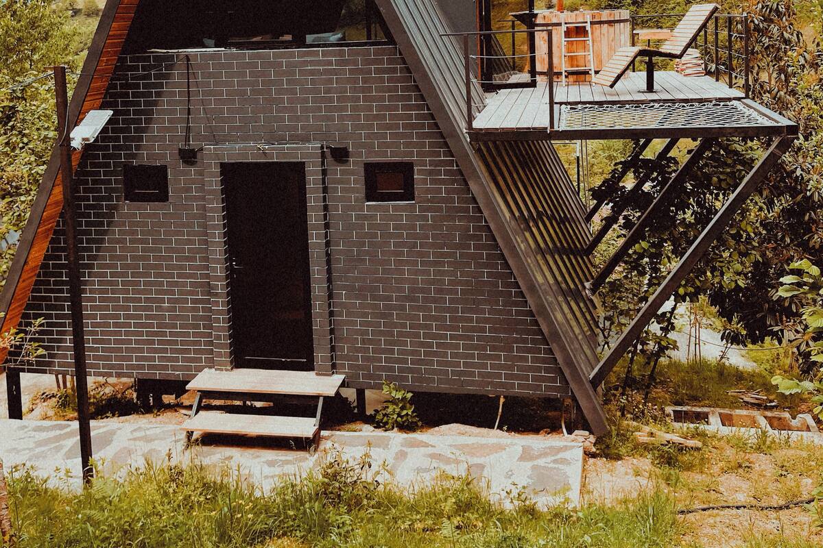 Un edificio moderno de ladrillo con forma triangular, una entrada pequeña y una terraza de madera.