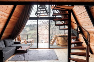 Un interior moderno con un ventanal grande, una escalera de madera y un sofá.