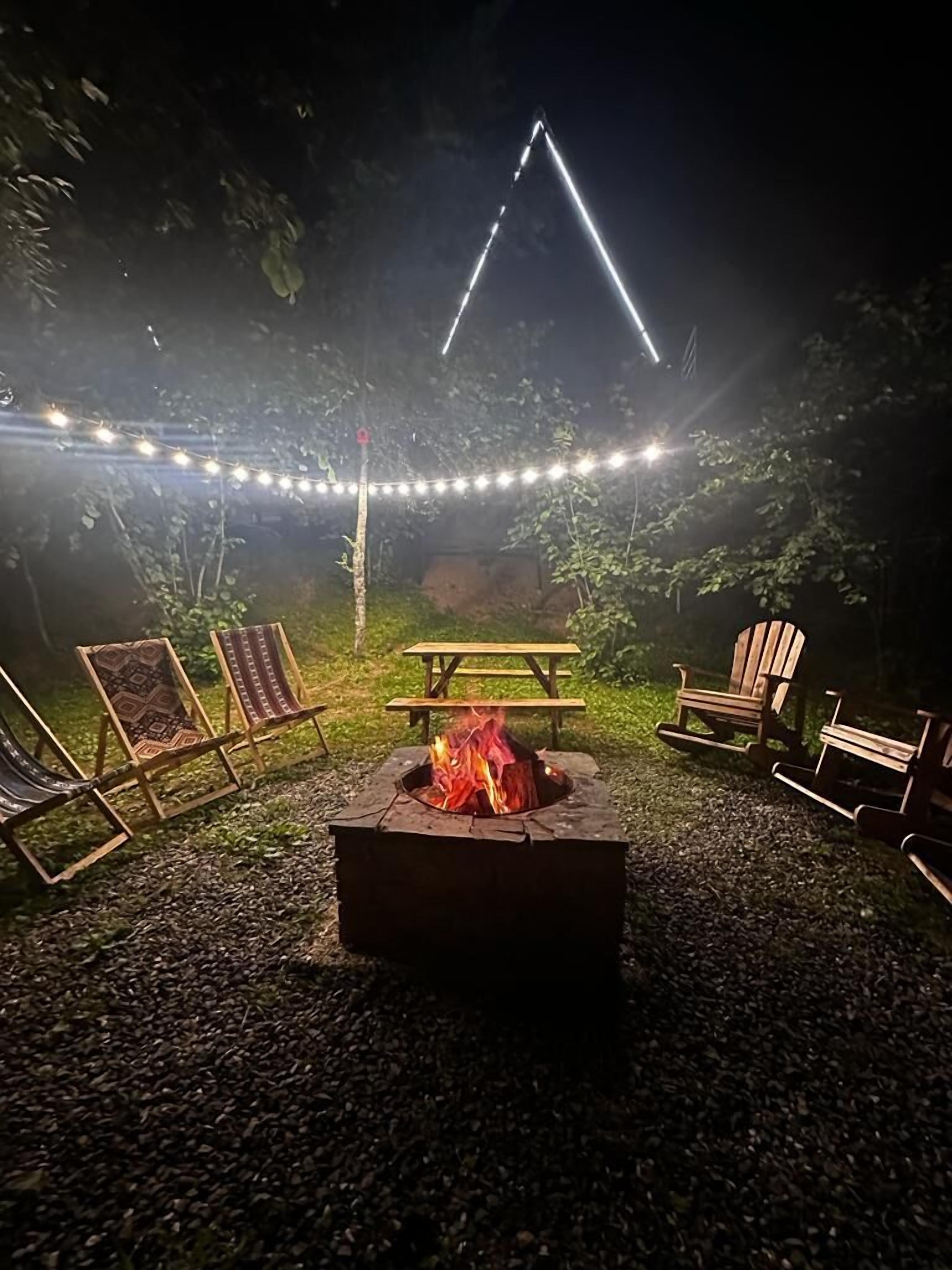 Un patio trasero con fogón, mesa de picnic y mobiliario exterior.