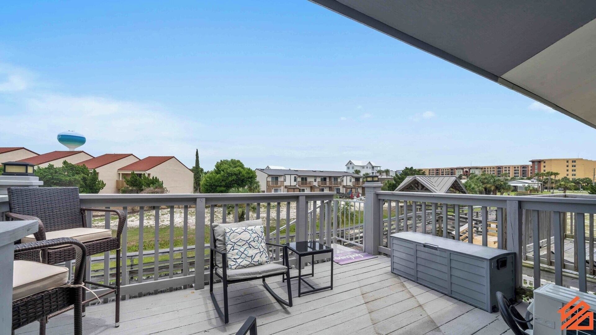 Una terrazza coperta all'aperto con mobili in vimini, un tavolino e un mobile contenitore.