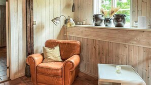 Una habitación acogedora con un sillón de cuero, una mesita pequeña y una ventana con paneles de madera.