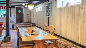 Un comedor de madera con una mesa larga, sillas y un centro de mesa con velas.