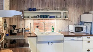Una cocina con gabinetes blancos, un lavamanos de acero inoxidable, un microondas y una cafetera.
