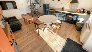 Cozinha moderna com ilha central, piso de madeira e área de jantar com mesa redonda e cadeiras.