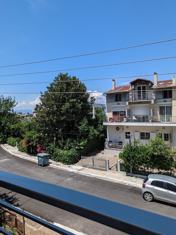 A two-story building with a balcony, a parked car, and a street view.