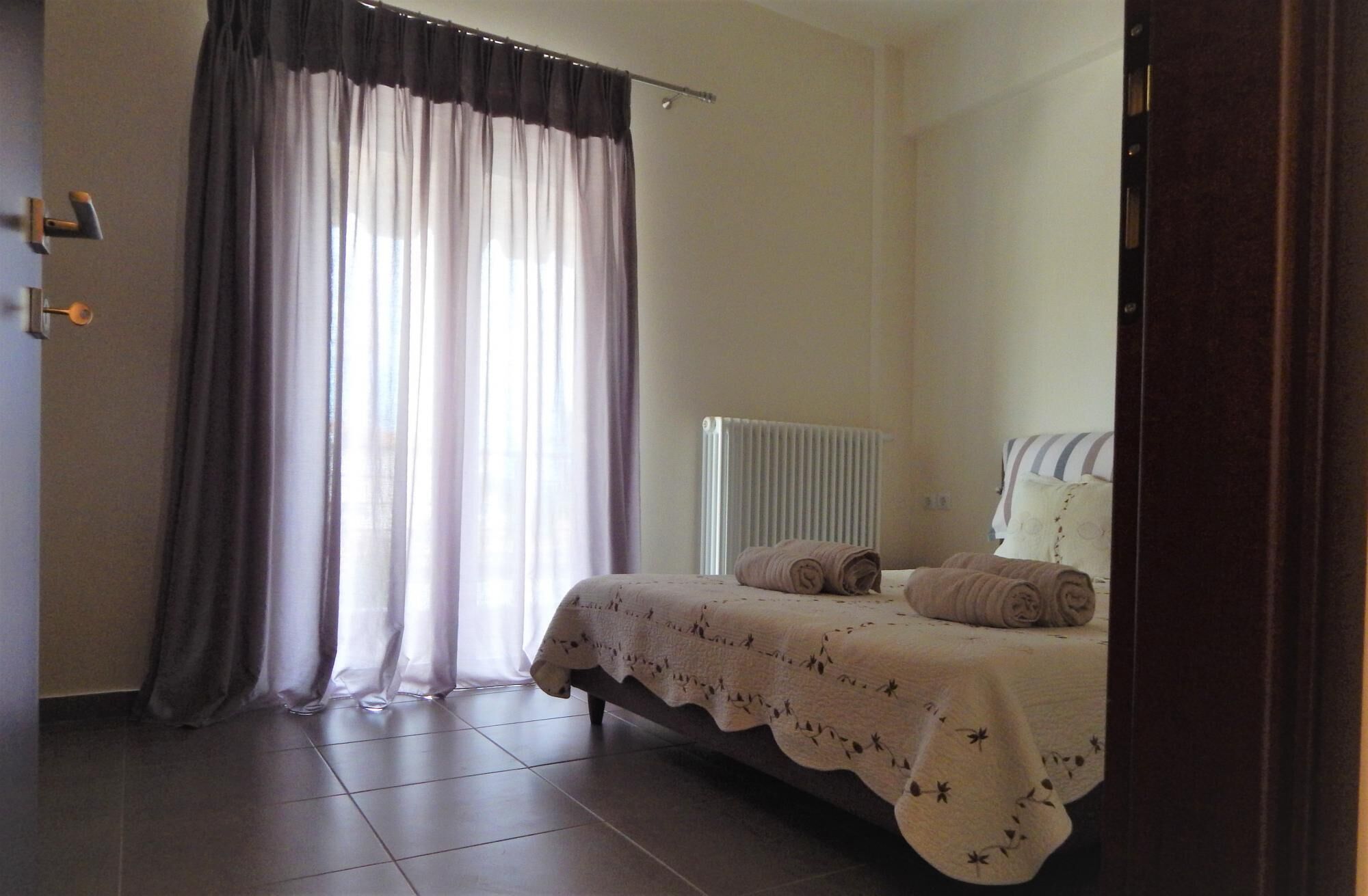 Een slaapkamer met een bed, een radiator en een raam met gordijnen.