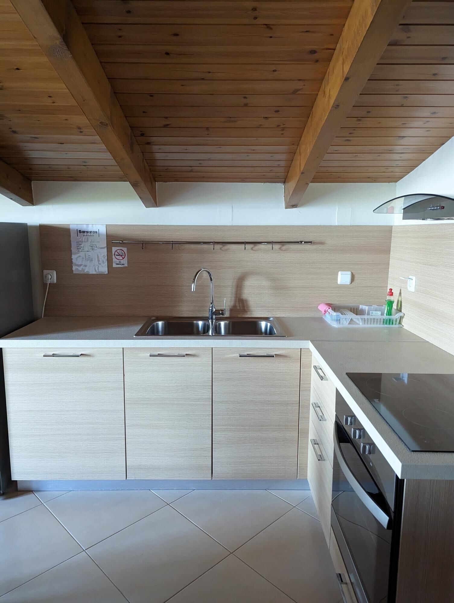 A modern kitchen with wooden beams, a stainless steel sink, and a built-in oven.