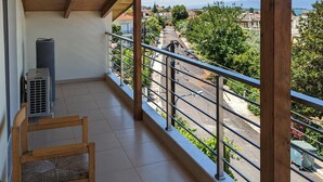 Ein Balkon mit Holzboden, Blick auf eine Wohngegend und eine abgestellte Klimaanlage.