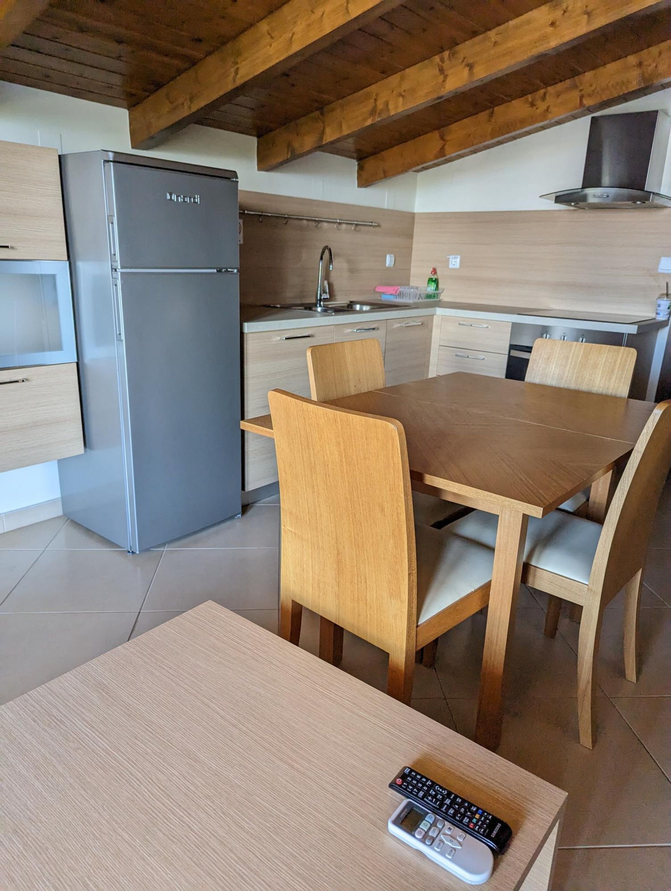 Una cocina moderna con refrigerador integrado, armarios de madera, una mesa de comedor con sillas y una isla de cocina.