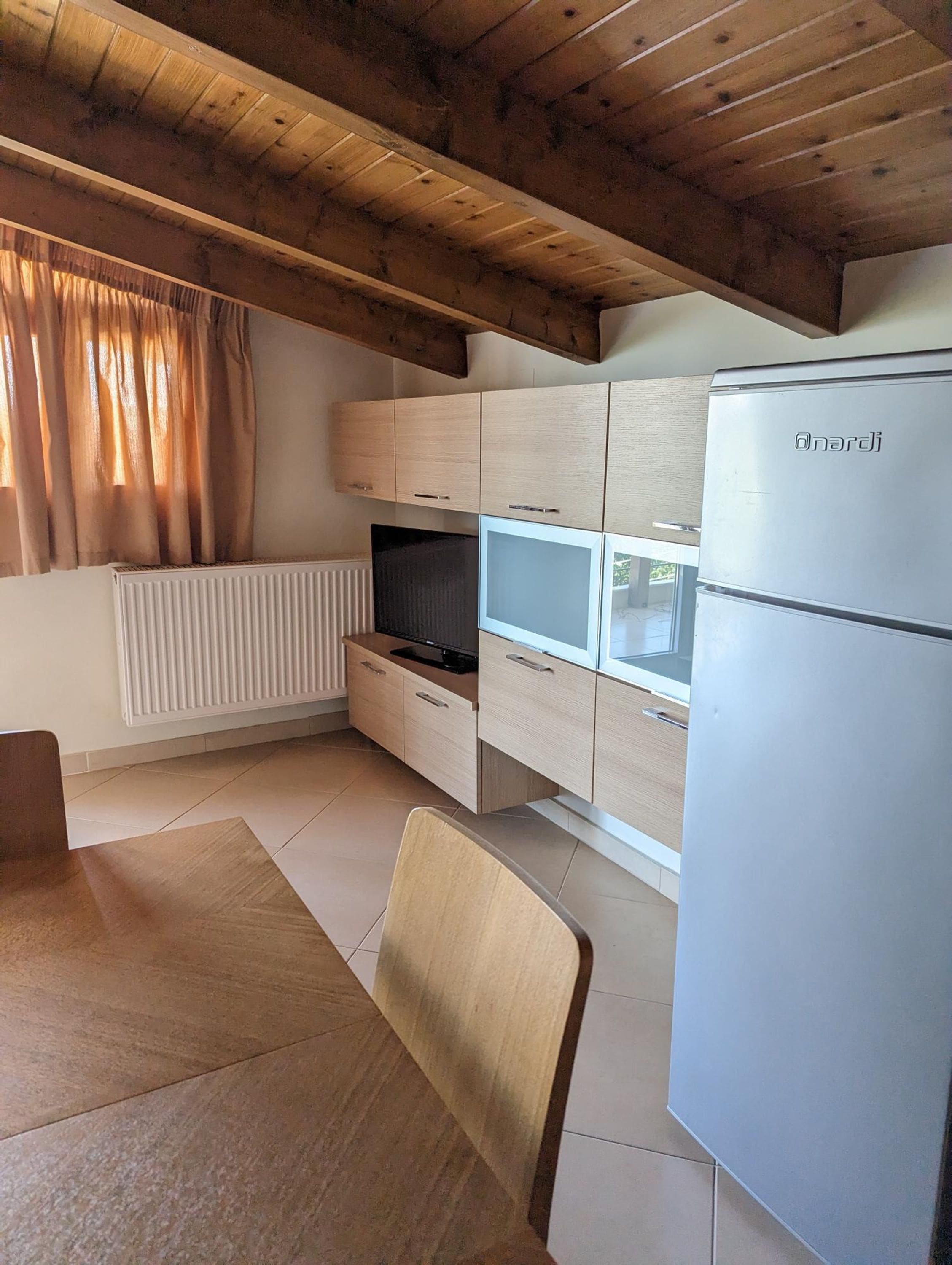 A compact kitchen with wooden cabinets, a built-in oven, and a refrigerator.