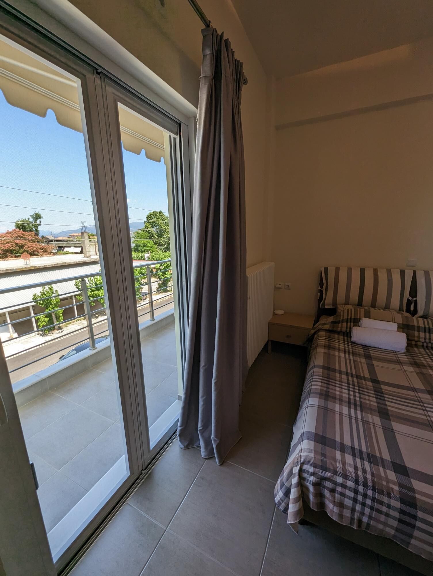 Ein Schlafzimmer mit Bett, Heizkörper und Blick nach außen.