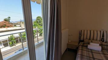 Ein Schlafzimmer mit Bett, Heizkörper und Blick nach außen.