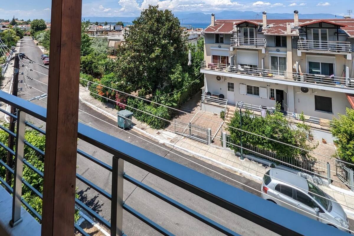 Ein Balkon mit Holzgeländer mit Blick auf ein Wohngebiet mit Häusern und einer Straße.