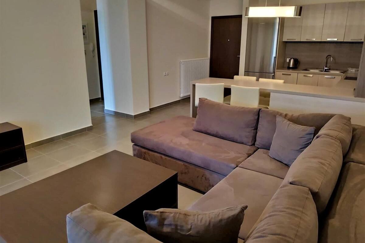 Ein modernes Wohnzimmer mit einem Ecksofa, einem Couchtisch und einem Essbereich mit Tisch und Stühlen.