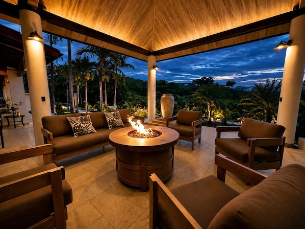 Un espace extérieur aménagé, abrité et doté d’un foyer, de mobilier en bois et d’une vue sur le ciel.