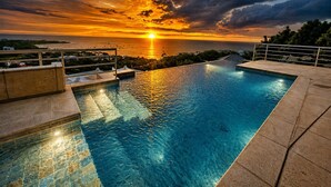 En pool med utsikt över solnedgången, ett räcke och en klar himmel.