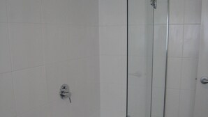 A bathroom with a glass-enclosed shower, a white bathtub, and white tiled walls. - Comfy family holiday destination (Ocean Grove)