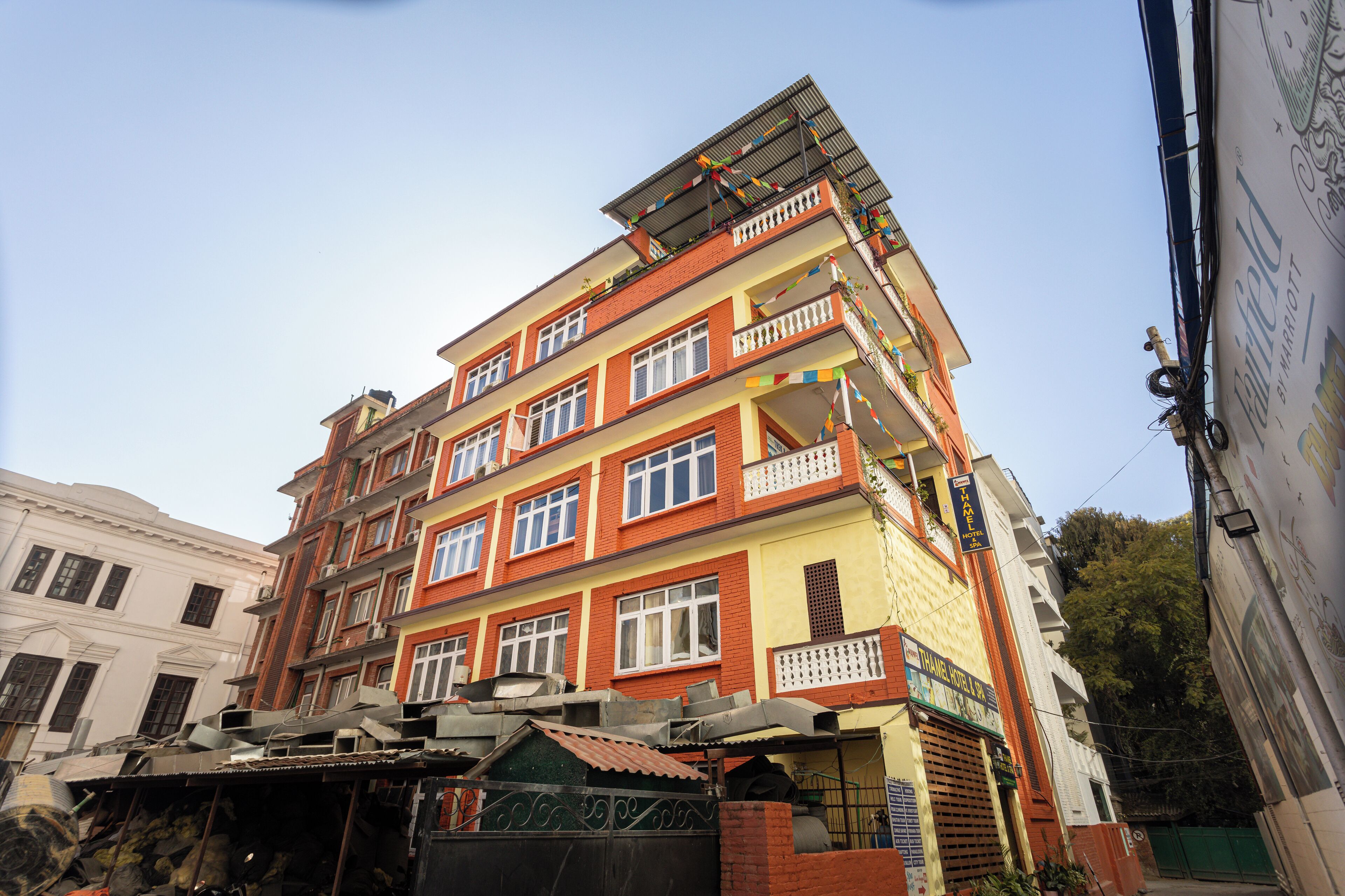 A multi-story building with balconies, a sign indicating a hotel, and a green gate.