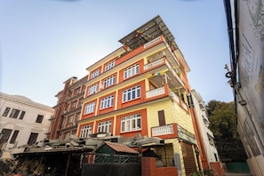 A multi-story building with balconies, a sign indicating a hotel, and a green gate. - Thamel Hotel & Spa (Kathmandu)