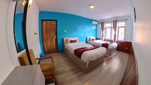 A hotel room with two beds, a desk, a chair, a wooden door, and a window with curtains. - Thamel Hotel & Spa (Kathmandu)