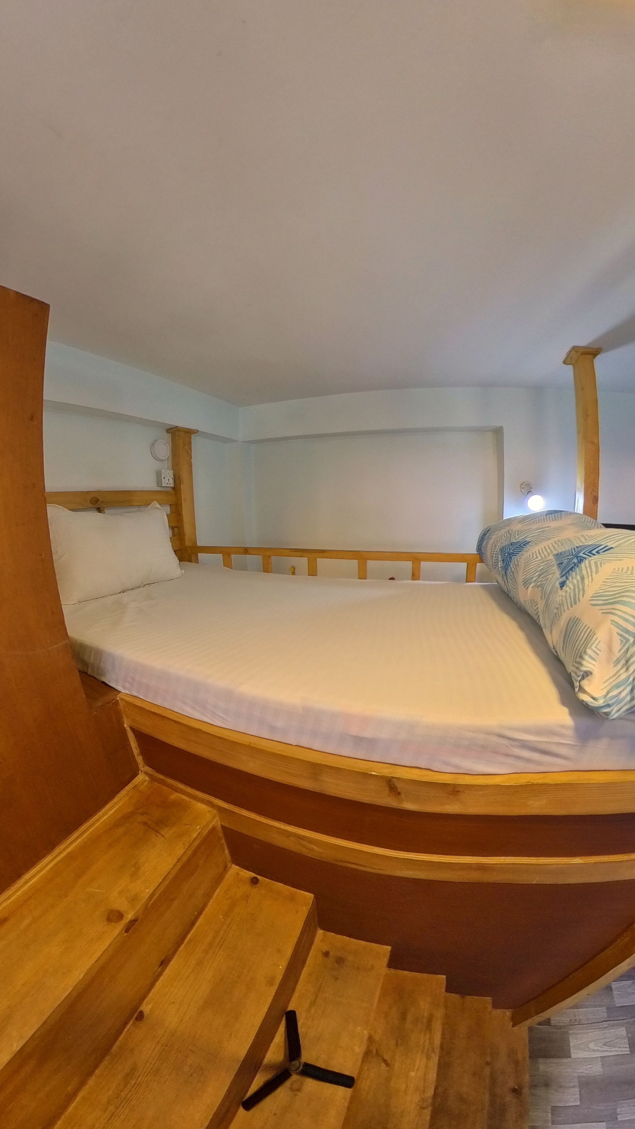 Un lit superposé avec une tête de lit en bois et un lit simple en dessous.