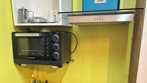 A compact kitchen with a microwave, toaster, sink, and a small refrigerator.