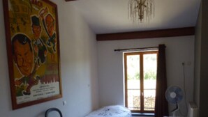 A room with two single beds, a chair, a fan, and a large poster on the wall. - Ferienwohnung mit Beheizten Pool bis 5 Personen (Marsaz)