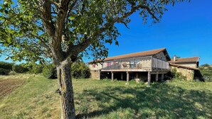 A rustic house with a balcony, surrounded by a grassy field and a large tree. - Ferienwohnung mit Beheizten Pool bis 5 Personen (Marsaz)